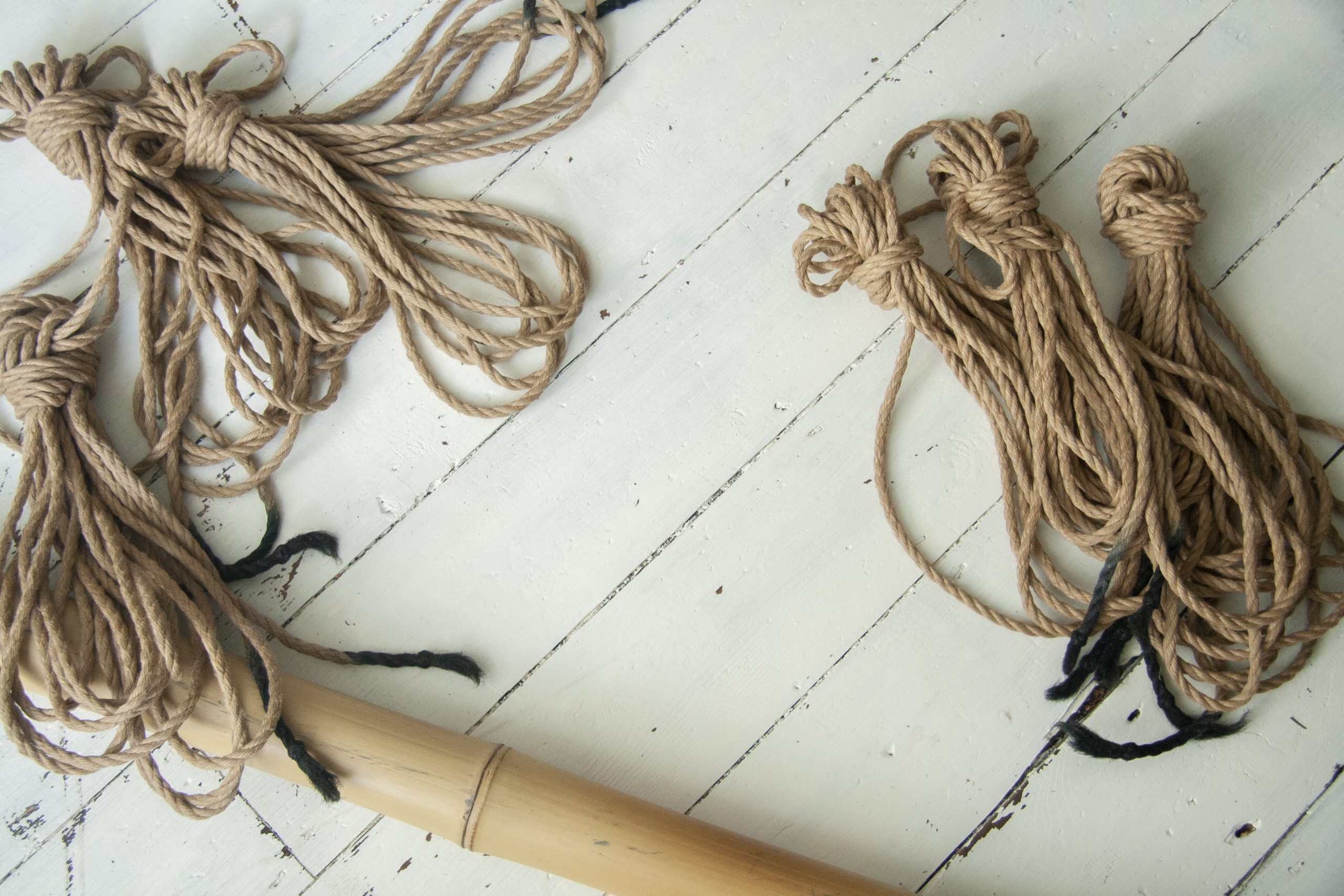 Photo of jute ropes and a bamboo scattered on white floorboards.